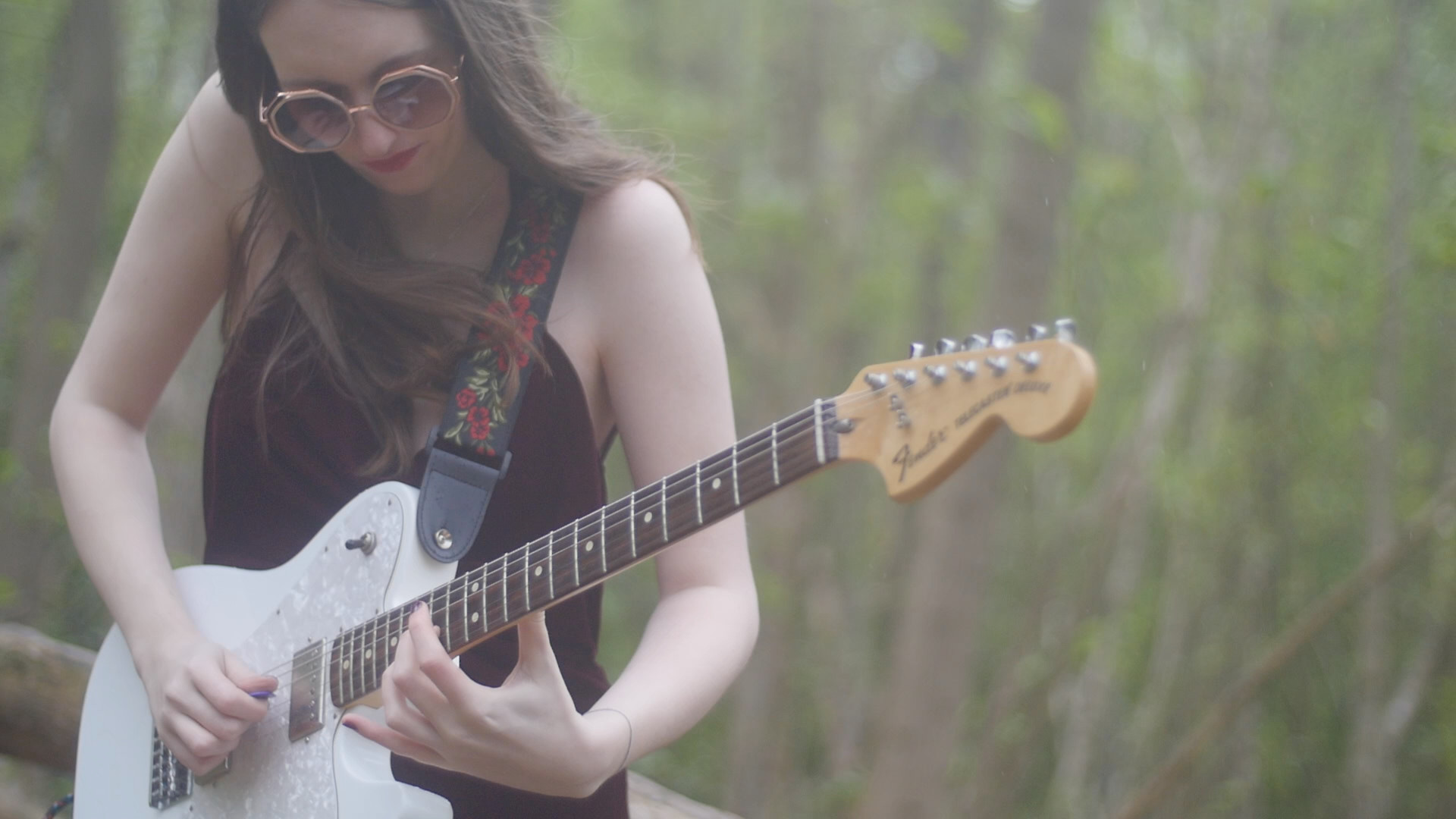 A photo of Grace playing her white fender telecaster in the forest, taken from the music video 'Where am I?'